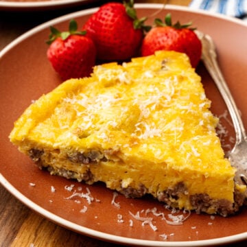 Perfectly cooked slice of a gluten free frittata on a plate with strawberries beside it.