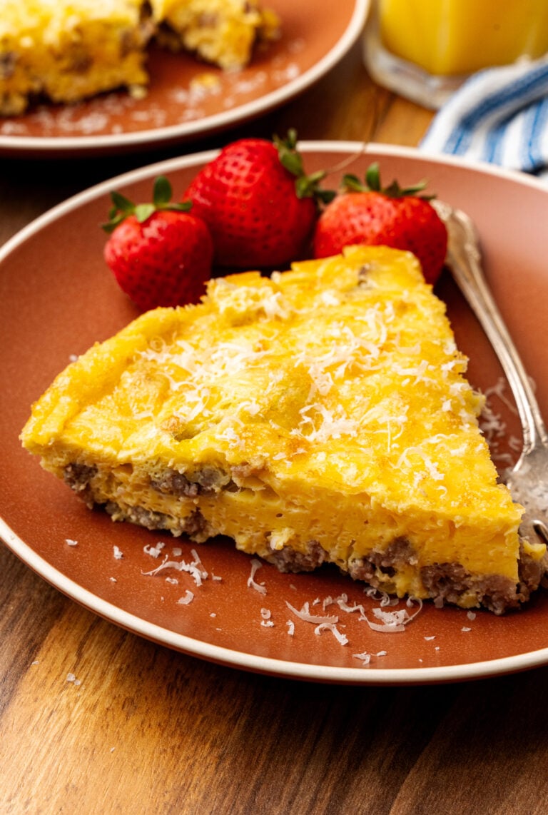 Perfectly cooked slice of a gluten free frittata on a plate with strawberries beside it.