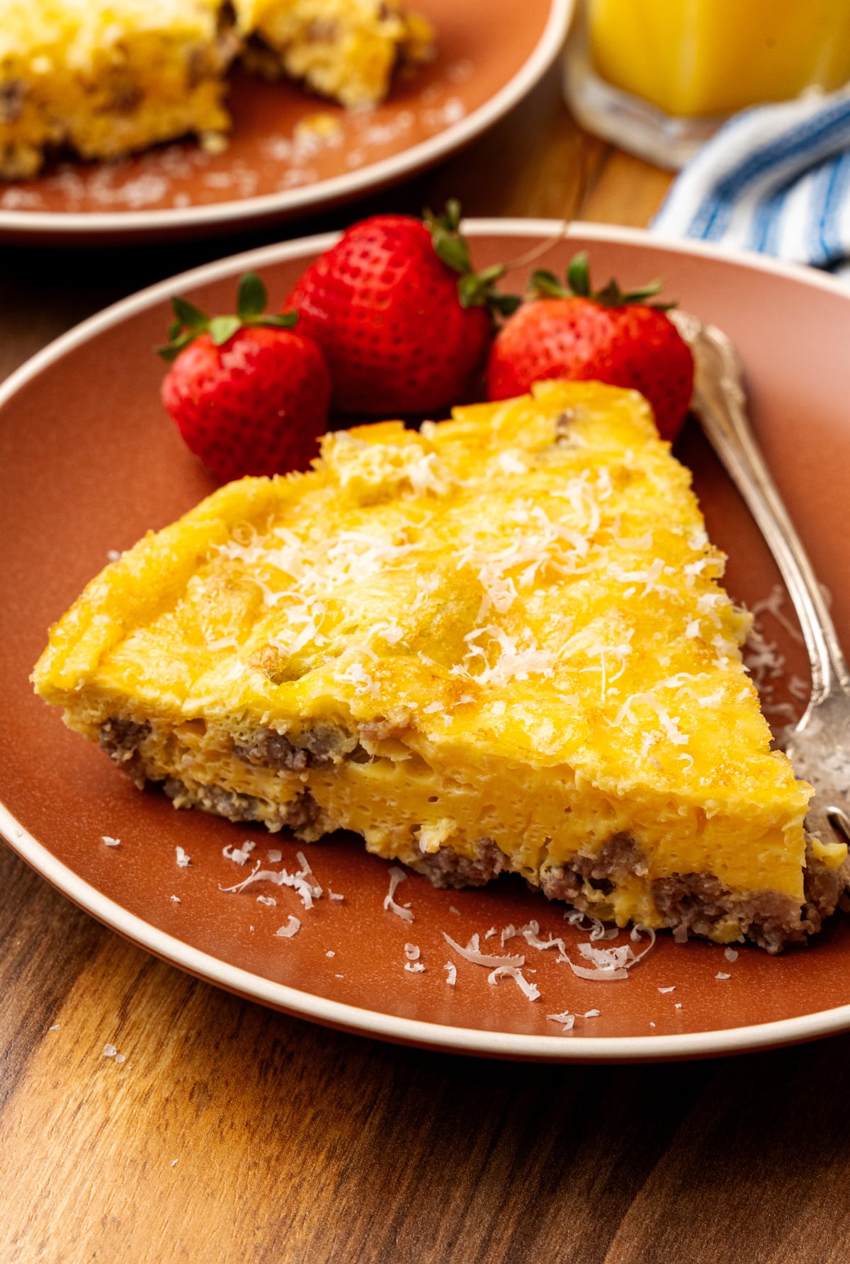Perfectly cooked slice of a gluten free frittata on a plate with strawberries beside it.