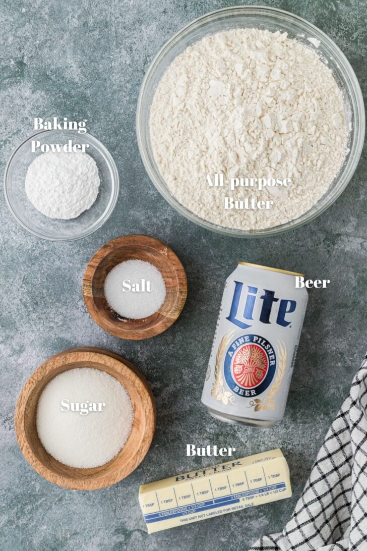 Ingredients for making beer bread. All purpose flour, baking powder, salt, sugar, beer and butter.