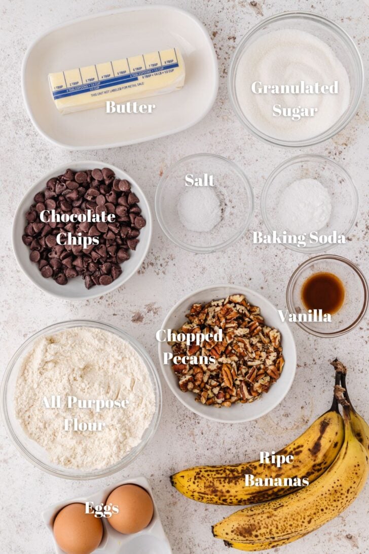 White and clear contains with butter, sugar, chocolate chips, salt, baking soda, chopped pecans, vanilla, flour and eggs.