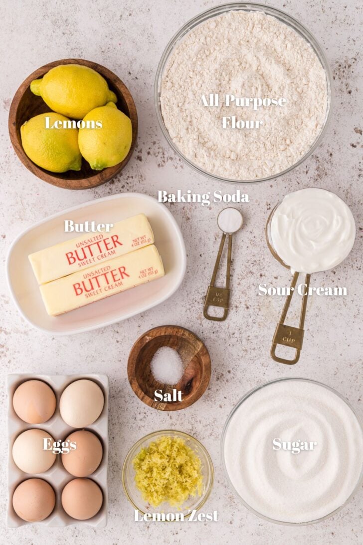 Flour, lemons, butter, baking soda, sour cream, salt, sugar, lemon zest and eggs in countainers to make lemon pound cake.