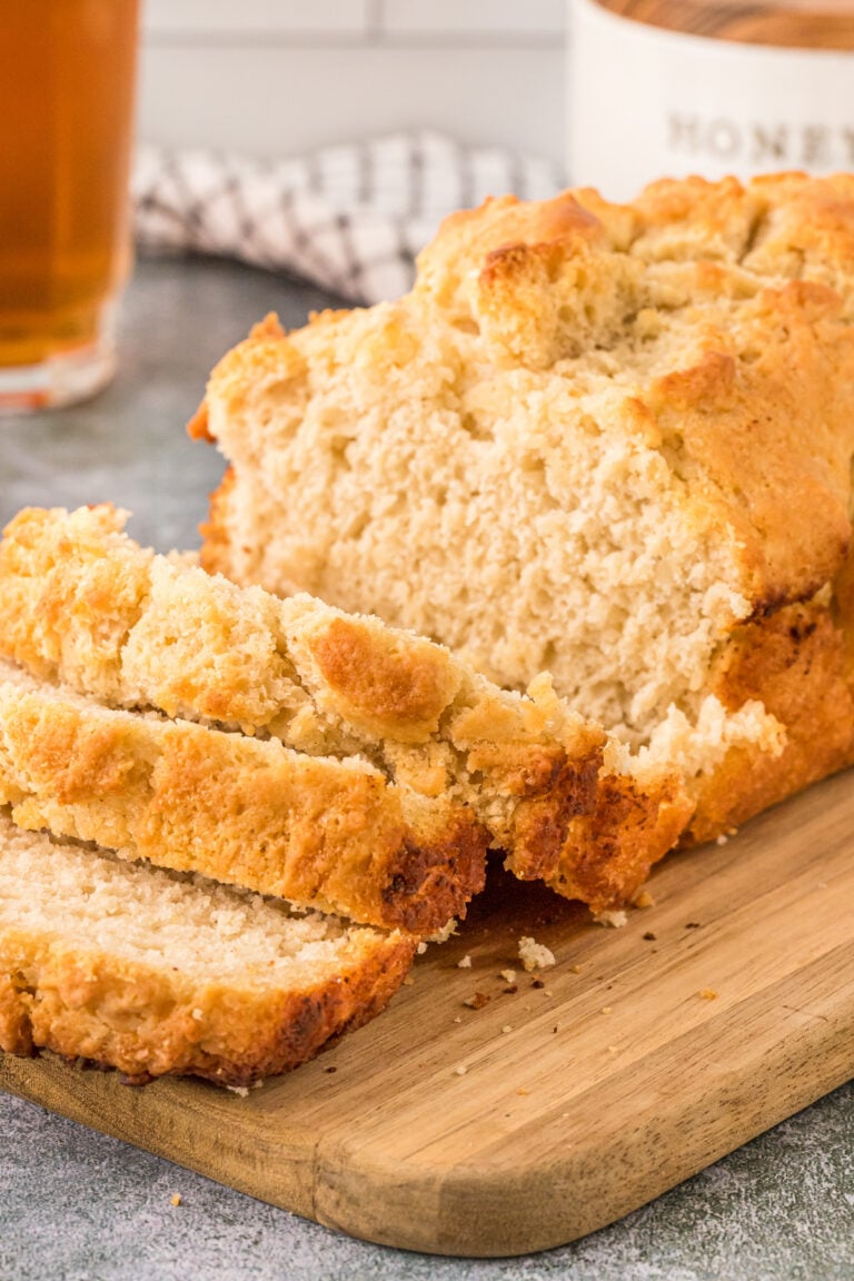 Beer bread sliced perfectly sitting on a wooden cutting board.
