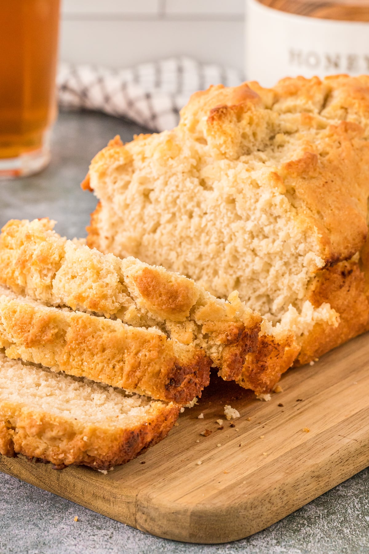 Beer bread sliced perfectly sitting on a wooden cutting board.