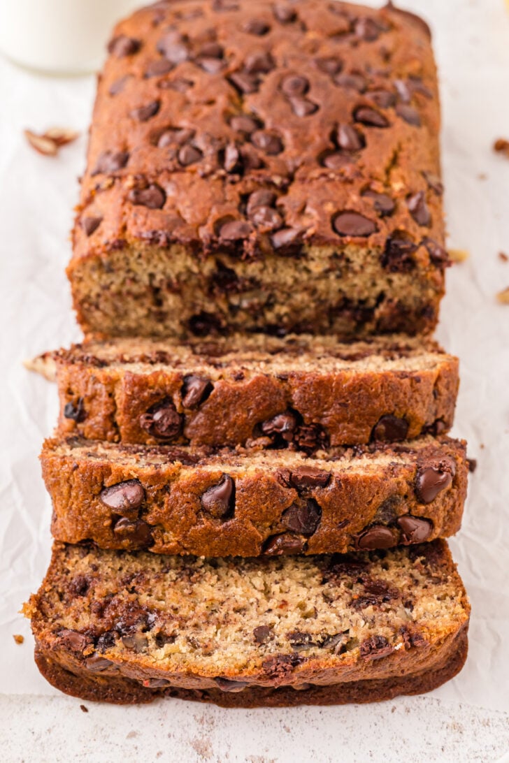 Sliced baked loaf of chocolate chip banana bread on parchment paper.