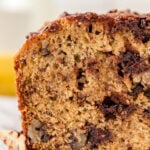 The corner of chocolate chip banana bread. the cross section has melty bits of chocolate and fluffy bread.