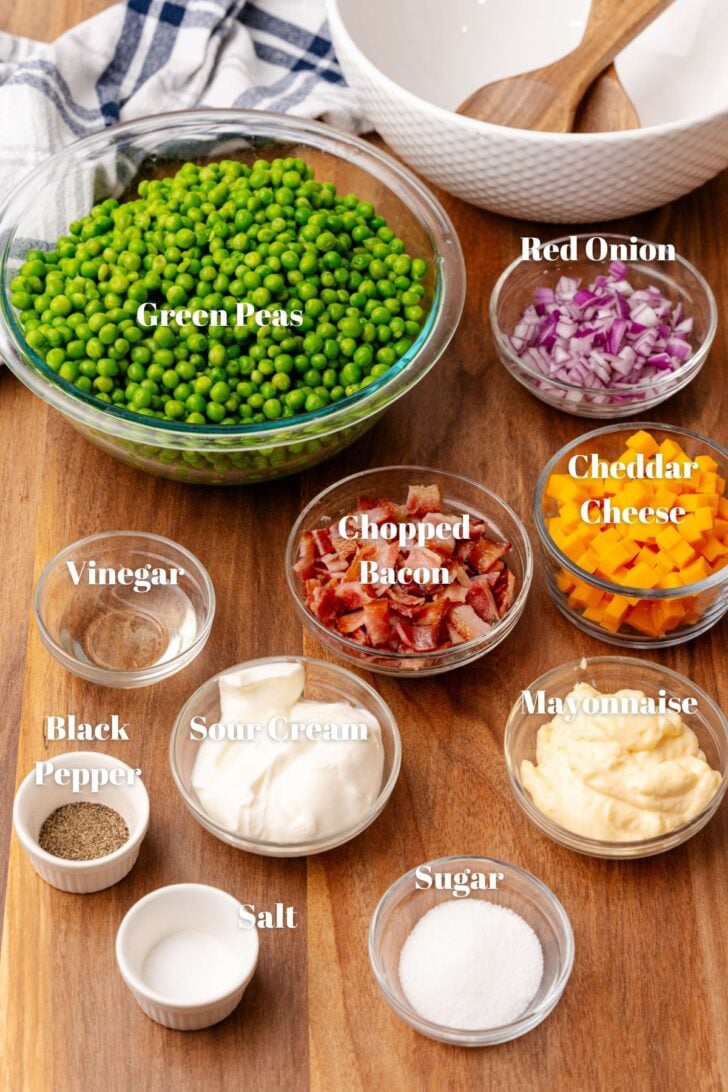 Glass containers with green peas, red onion, cheddar cheese, bacon, vinegar, sour cream, mayonnaise, salt pepper and sugar.