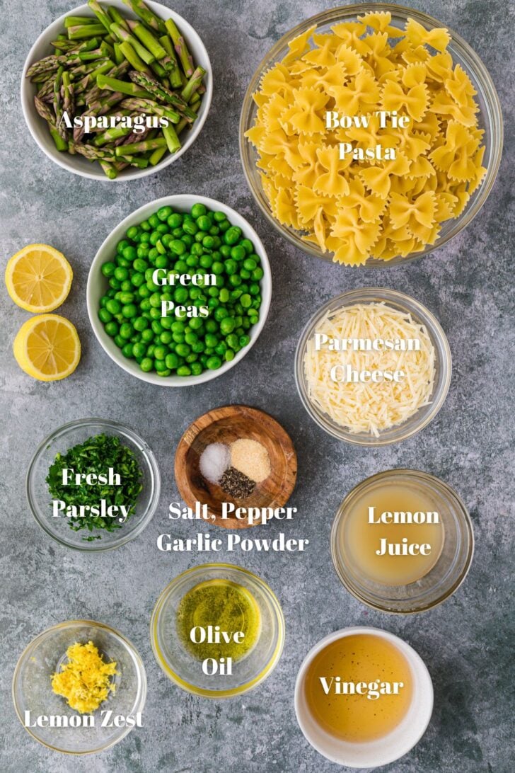 Bowls of fresh asparagus, bow tie pasta, green peas, Parmesan cheese, fresh parsley, lemon juice, salt, pepper, garlic powder, lemon zest , olive oil and vinegar.