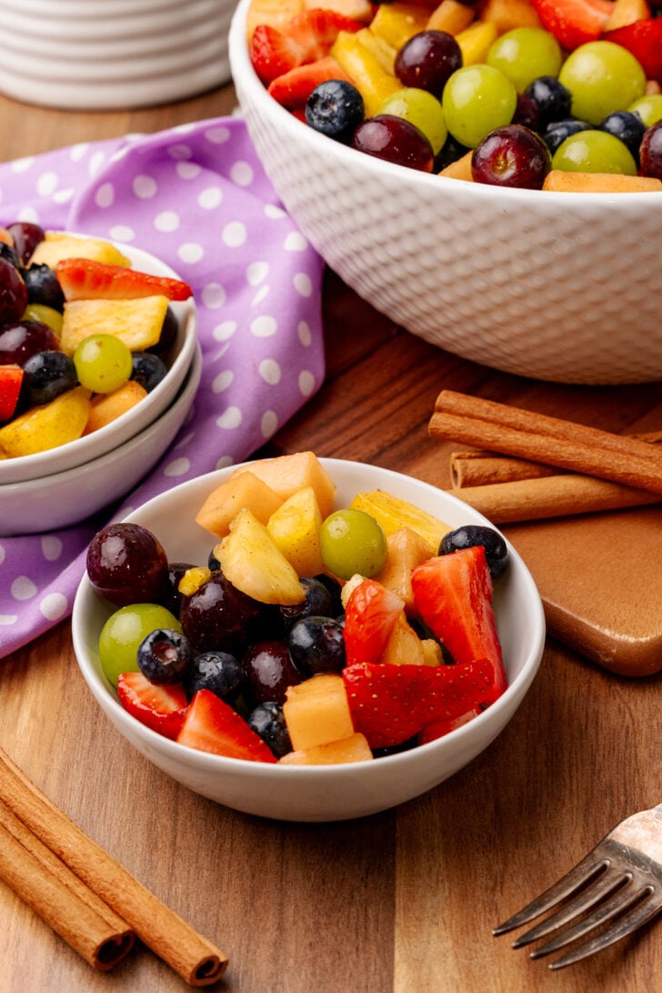 Small white boel with fresh fruit salad on a wooden counter.