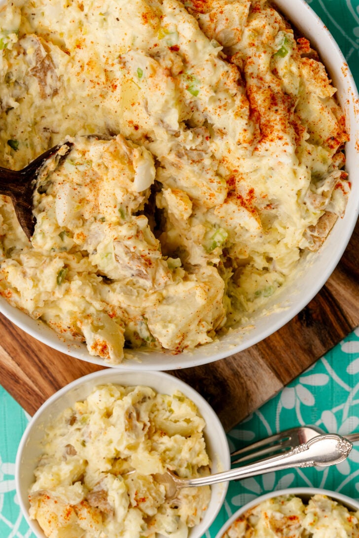 Potato salad scooped out of a bowl with a wooden spoon.