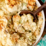 Potato salad scooped out of a bowl with a wooden spoon.