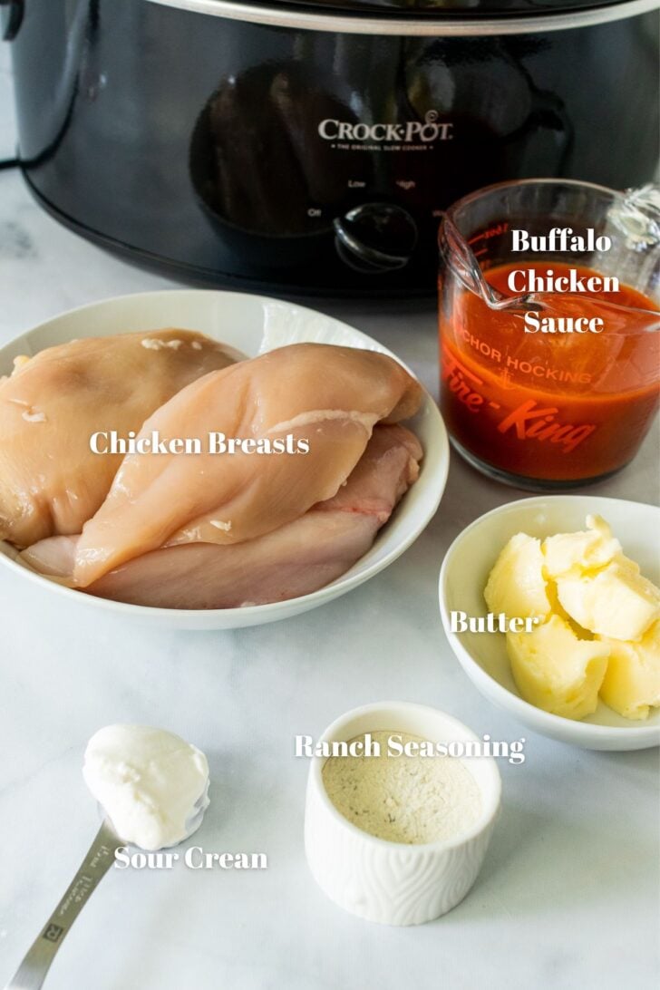 Ingredients used for crock pot buffalo chicken. Buffalo sauce, chicken breast, butter, ranch seasoning and sour cream.