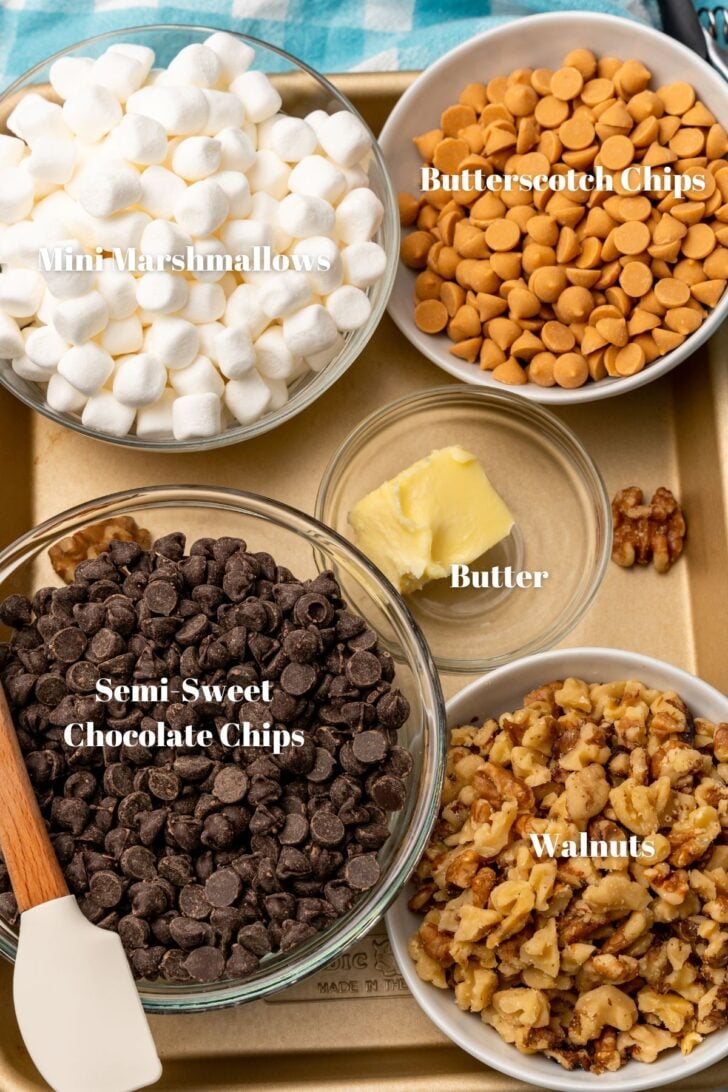Ingredients used to make rocky road candy clusters. Mini marshmallows, butterscotch chips, butter, chocolate chips and walnuts.