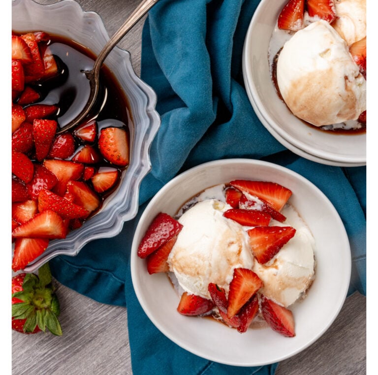Bowl with red strawberries and balsamic glaze in it.