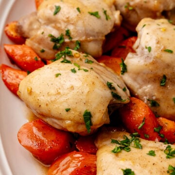 Sheet Pan Honey Glazed Chicken Thighs with roasted red peppers garnished with fresh parsley on white plate