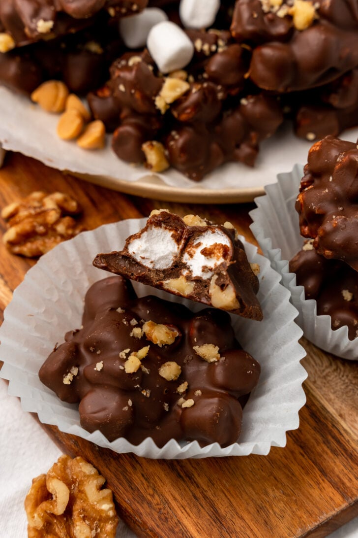 Rocky road candy clusters sitting in a cupcake wrapper cut in half exposing the butter scotch and marshmallow topping.