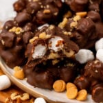 Rocky road clusters 13 with chocolate, marshmallows, and peanuts on a cream plate with scattered toppings