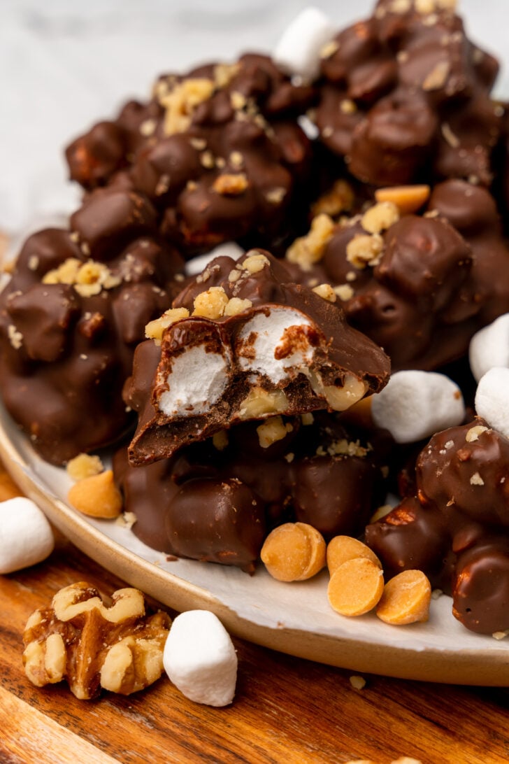 Rocky road clusters 13 with chocolate, marshmallows, and peanuts on a cream plate with scattered toppings