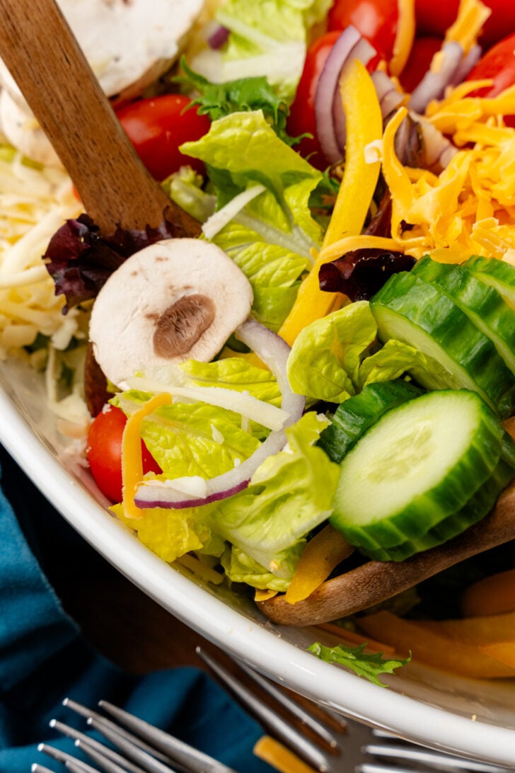 Lettuce, tomatoes, cucumbers, mushrooms and onion tossed with a wooden spoon.