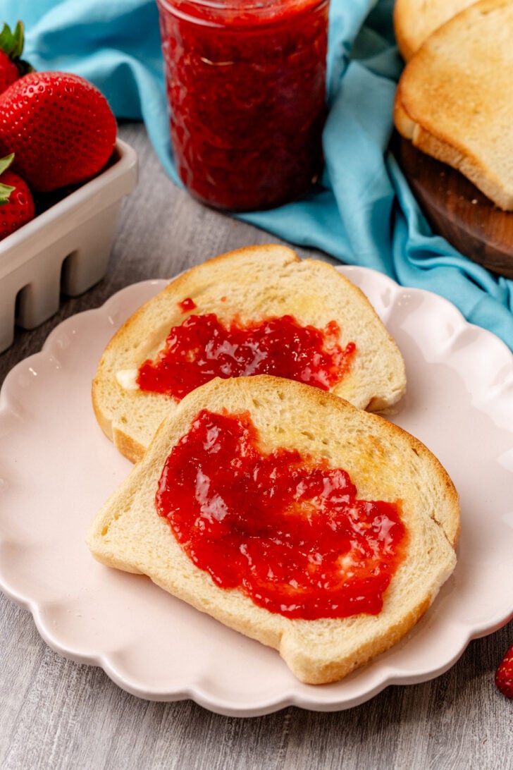 Strawberry Jam slathered on toast on a white plate.