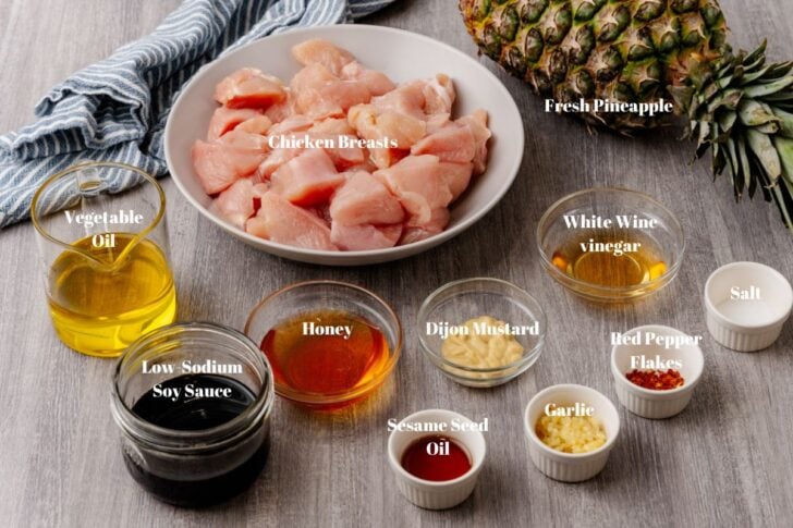 Ingredients to make pineapple chicken skewers. chicken breast, vegetable oil, pineapple, white wine vinegar, salt, red pepper flakes, garlic, sesame seed oil, low sodium soy sauce, honey and dijon mustard.