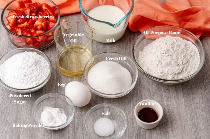 Ingredients used to make strawberry bread. powdered sugar, egg, vegetable oil, strawberries, milk, flour, vanilla, baking powered and salt.