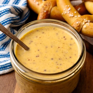 Honey mustard in a small glass jar served with a spoon.