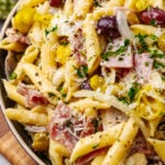 Italian pasta salad 2 5 with penne, ham, olives, and cheese in a tan bowl on wooden surface, overhead view