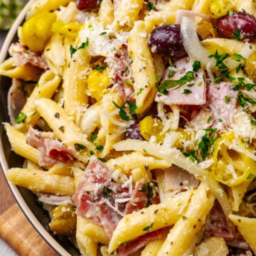 Italian pasta salad 2 5 with penne, ham, olives, and cheese in a tan bowl on wooden surface, overhead view