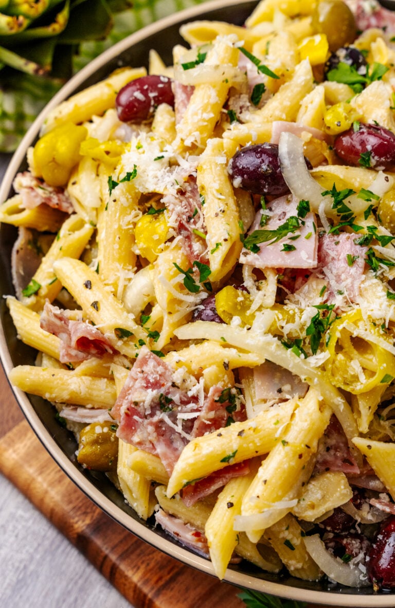 Italian pasta salad 2 5 with penne, ham, olives, and cheese in a tan bowl on wooden surface, overhead view