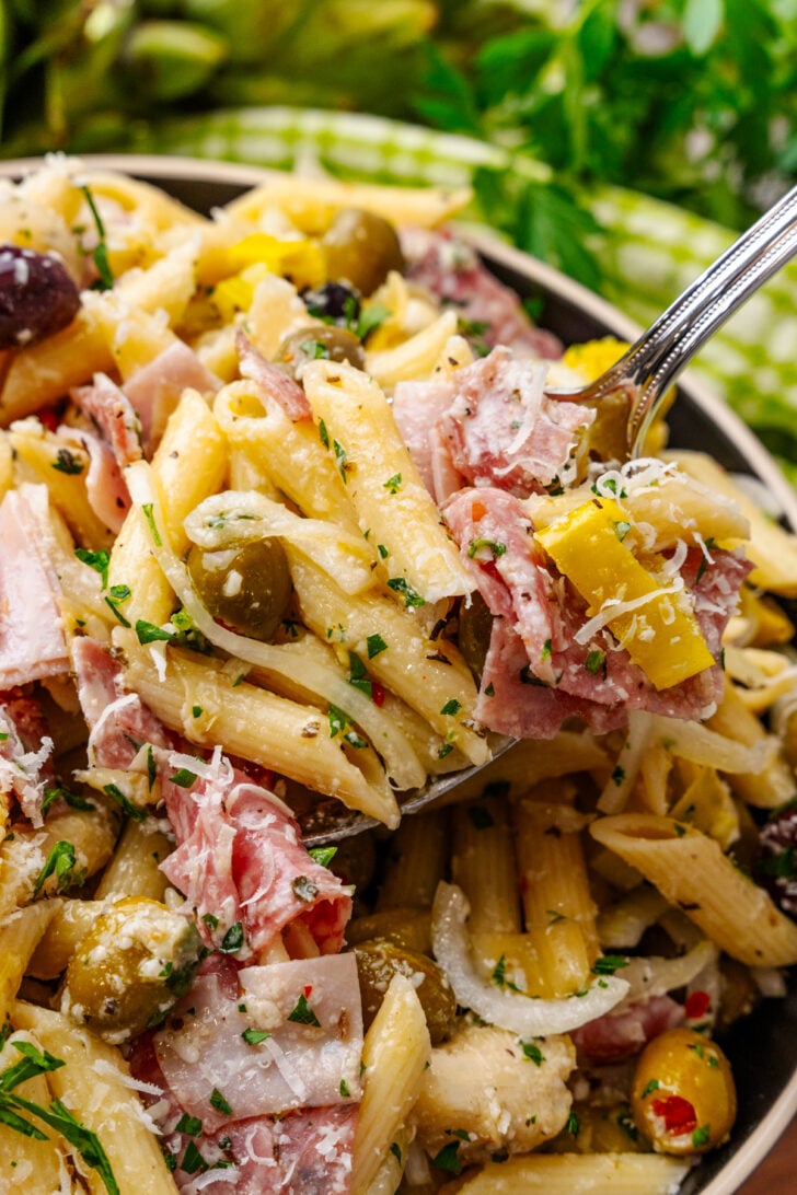 Italian pasta salad sitting in a bowl topped with onions and cheese.