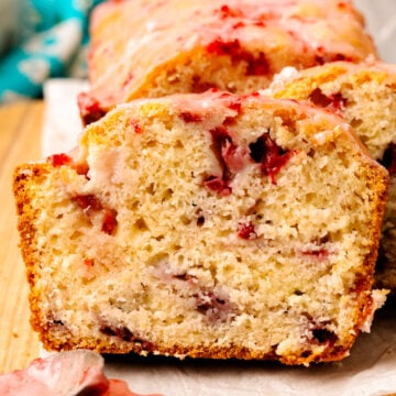 Sliced strawberry bread with fresh strawberries on a cutting board