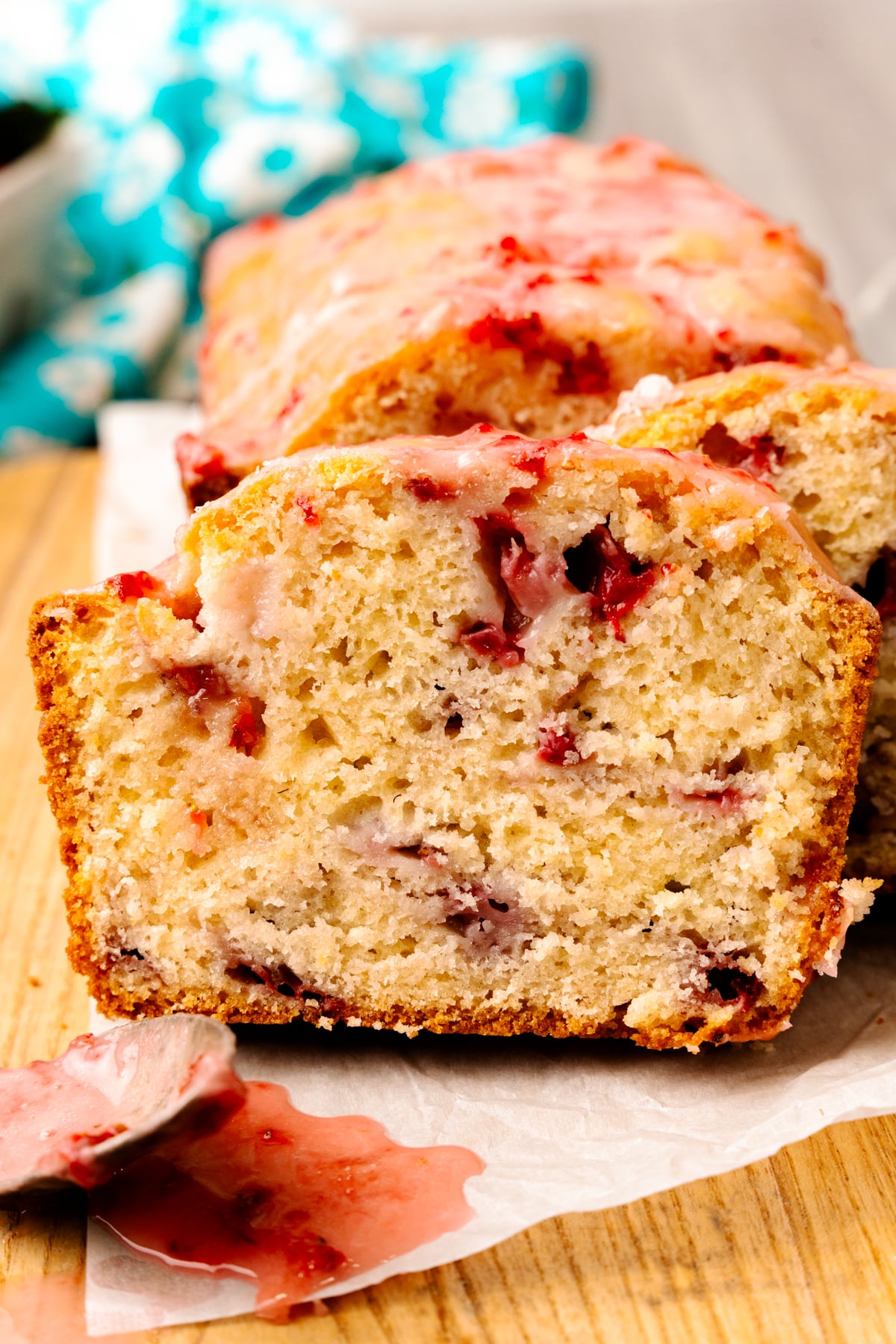 Sliced strawberry bread with fresh strawberries on a cutting board