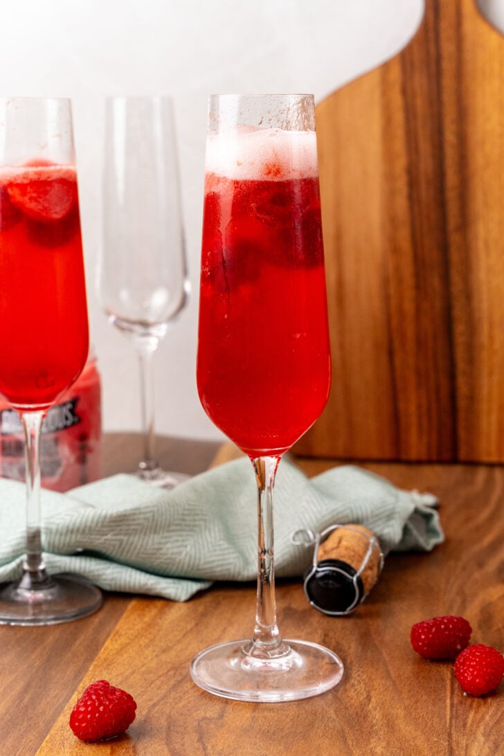 Glass with red raspberry mimosa with a layer of fizz on top.