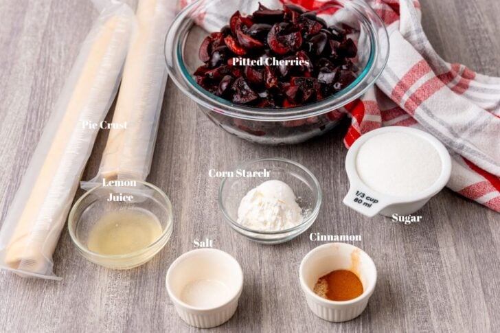 Fresh cherries, pie dough, lemon juice, sugar, cinnamon, salt and corn starch in glass containers.