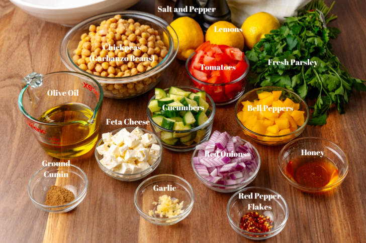 Ingredients for fresh Chickpea Salad and homemade dressing in clear glass bowls.