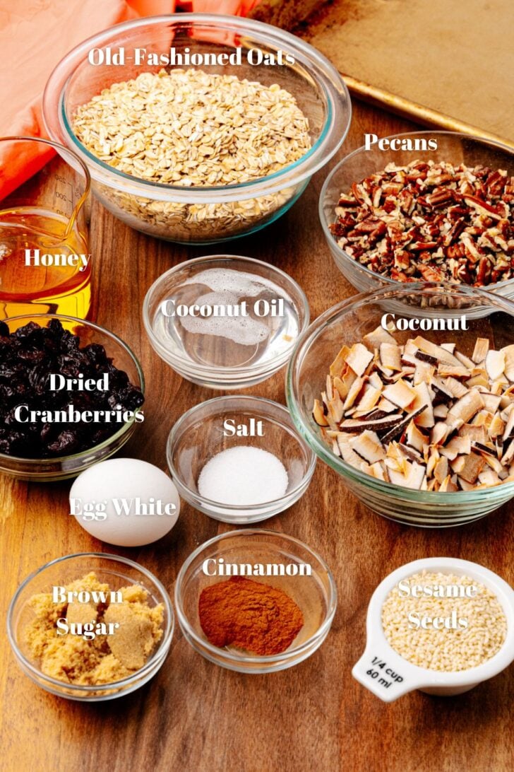 Ingredients to make homemade granola. Old fashioned oats, Pecans, coconut, coconut oil, honey, salt, egg white, dried cranberries, cinnamon, sesame seeds and brown sugar.