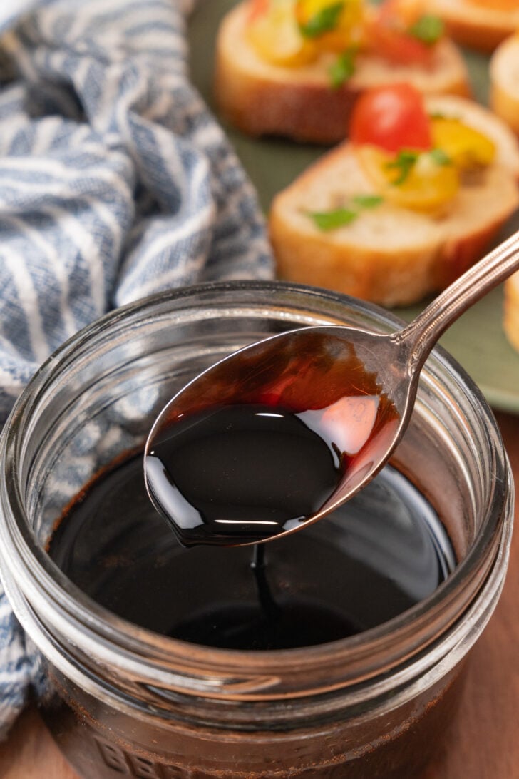 Silver spoon in a jar of balsamic reduction.