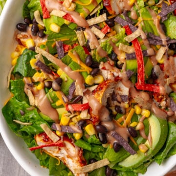 Easy BBQ Chicken Salad with crispy tortilla strips, black beans, corn, peppers, and creamy dressing in a white bowl