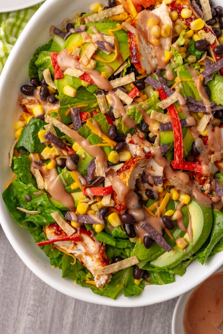 Easy BBQ Chicken Salad with crispy tortilla strips, black beans, corn, peppers, and creamy dressing in a white bowl
