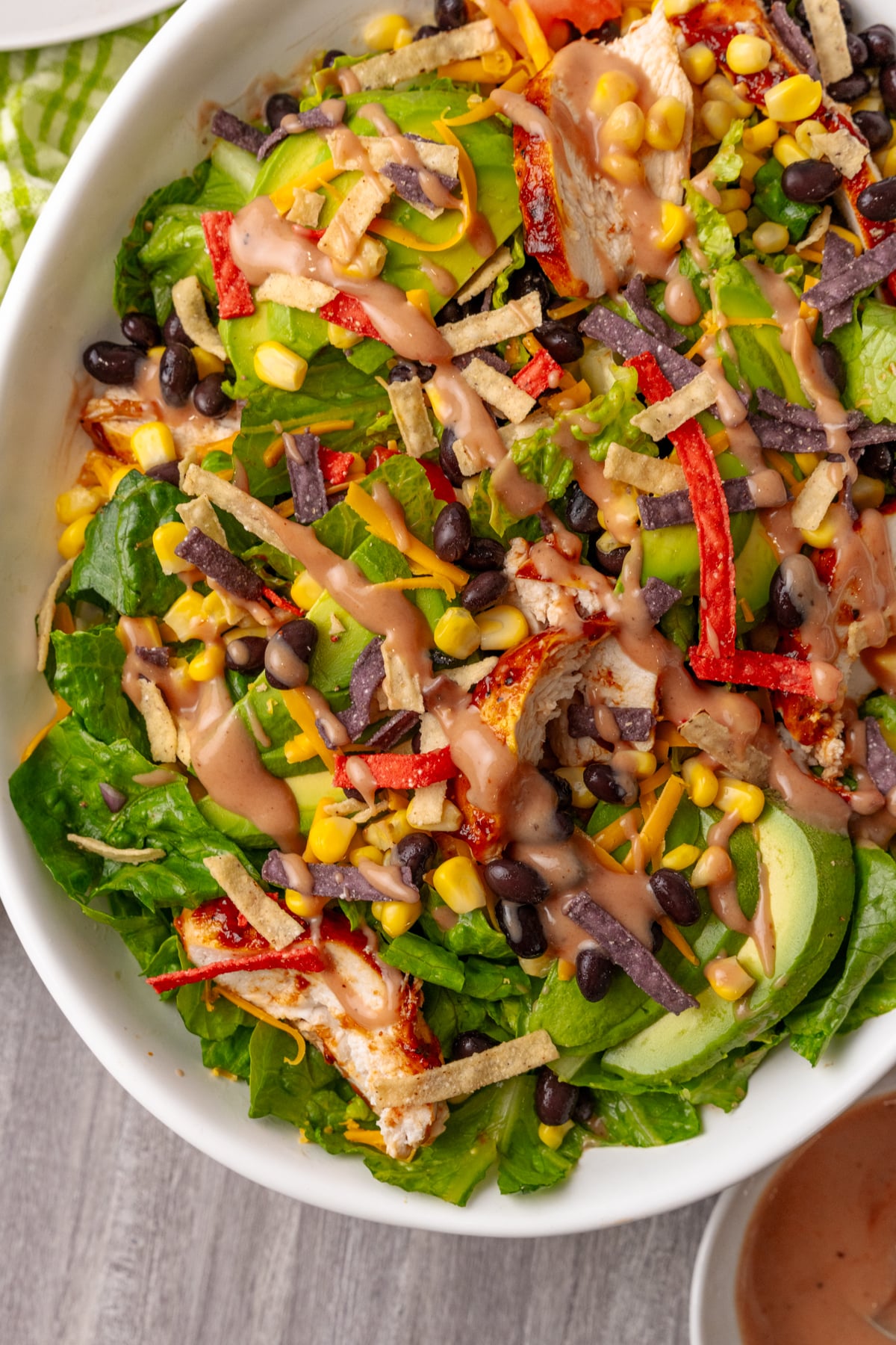 Easy BBQ Chicken Salad with crispy tortilla strips, black beans, corn, peppers, and creamy dressing in a white bowl
