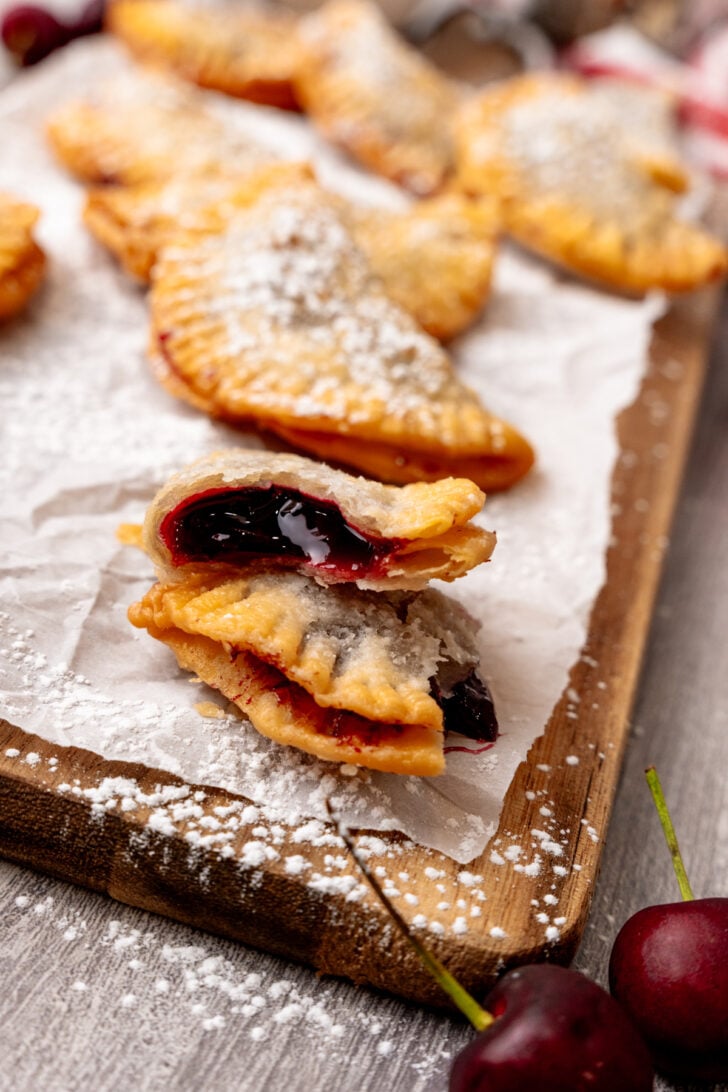 Fried cherry pie cut in half on a white parchment paper.