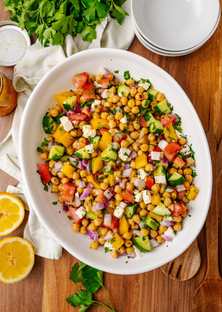 White serving bowl with fresh Chickpea salad drizzled with homemade dressing.