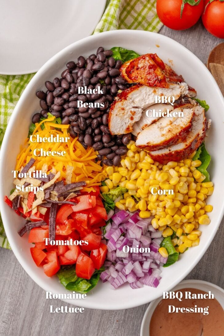 White bowl with chicken, black beans, corn, tomatoes, onion and cheese.