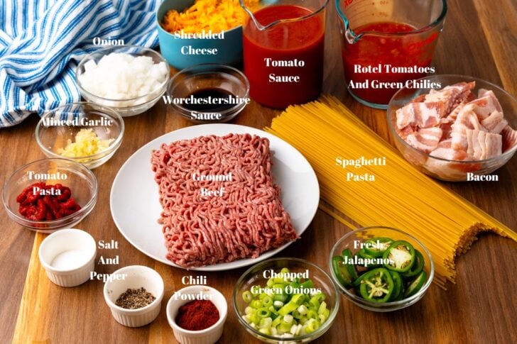 Ingredients in white or clear glass bowls for hearty Cowboy spaghetti made with ground beef and bacon.