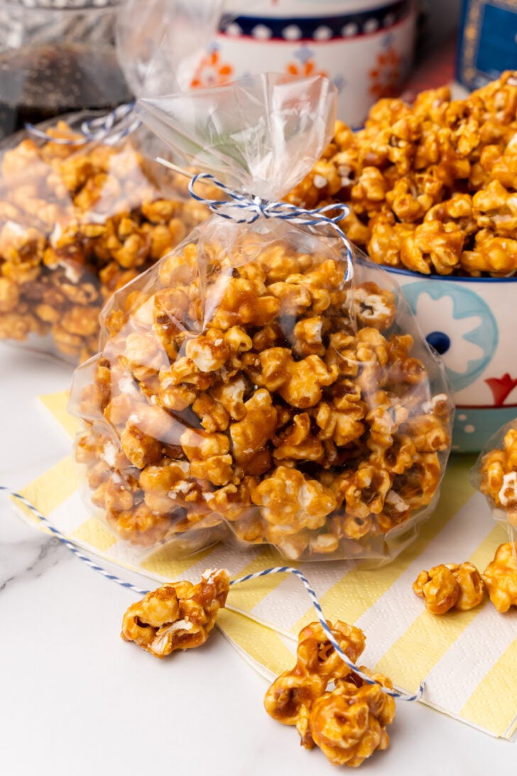 Homemade caramel corn in a clear bag tied with a blue string for gift giving.