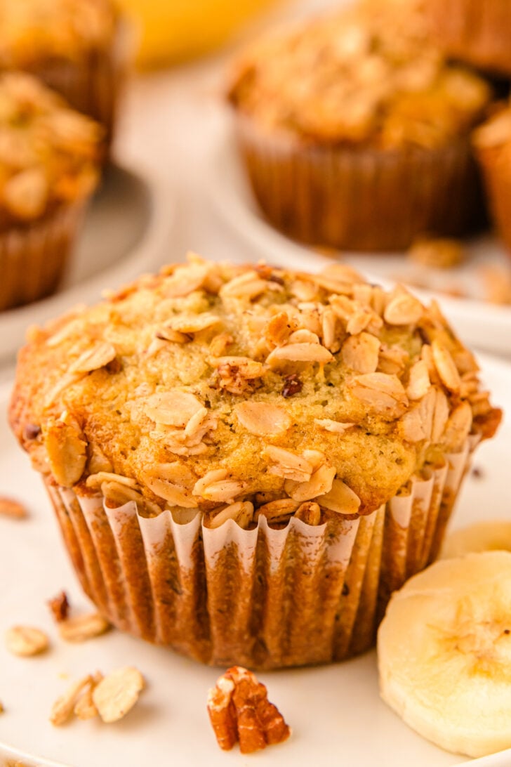 Banana Granola Muffin in a paper liner on a white plate.