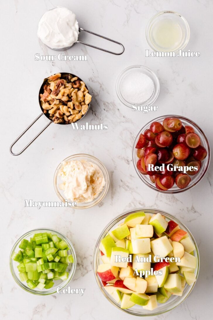 Dressing ingredients with apples, walnuts, grapes and celery for Waldorf Salad recipe.