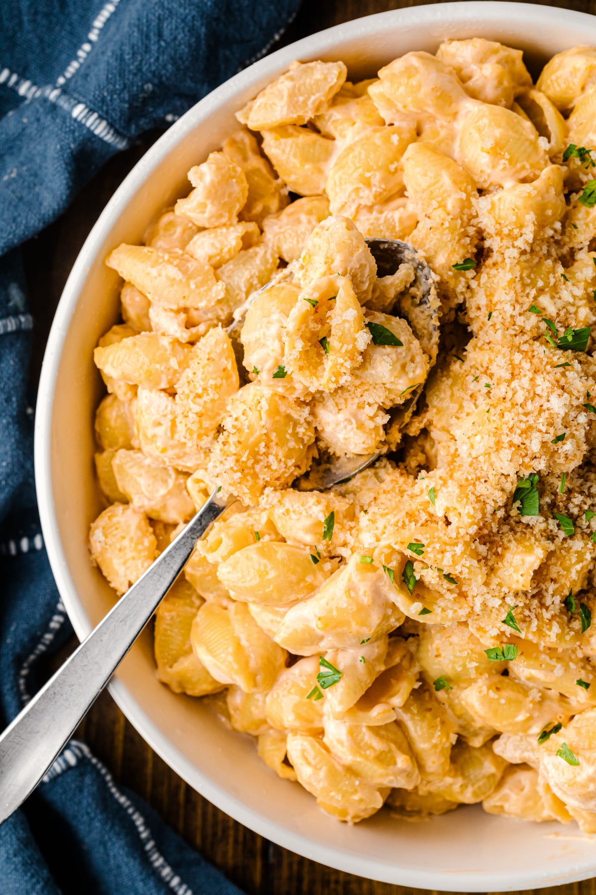 Easy Pasta Shells And Cheese in white bowl with spoon, topped with breadcrumbs and fresh parsley garnish
