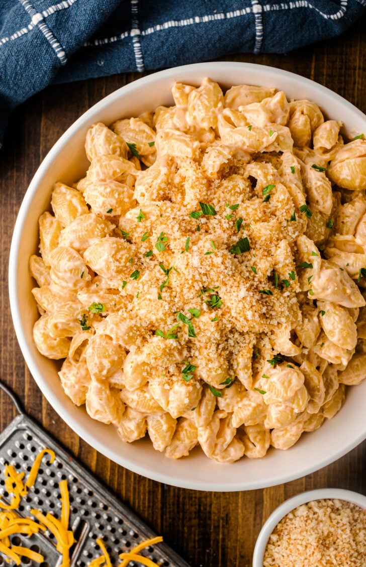 White bowl of creamy Shells and Cheese with panko breadcrumb topping.